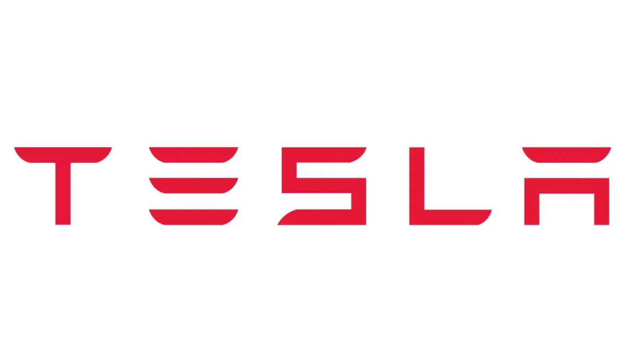 Czerwony napis TESLA na białym tle. Taki znaczek ma Tesla, symbol innowacji i przyszłości motoryzacji.