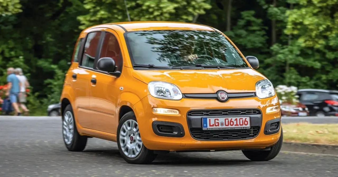 Pomarańczowy Fiat Panda 3 na drodze, z zielenią w tle.
