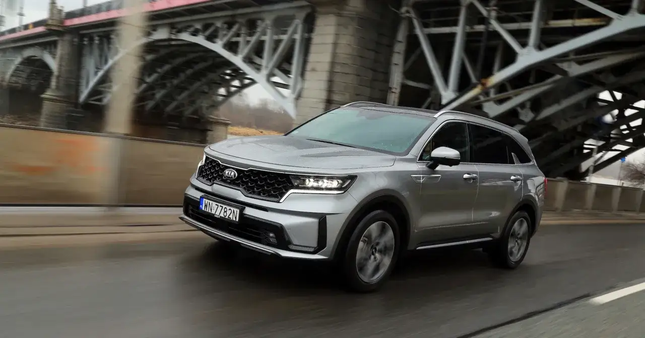 Srebrny Kia Sorento 2025 pędzi pod mostem, gotowy na każdą podróż.