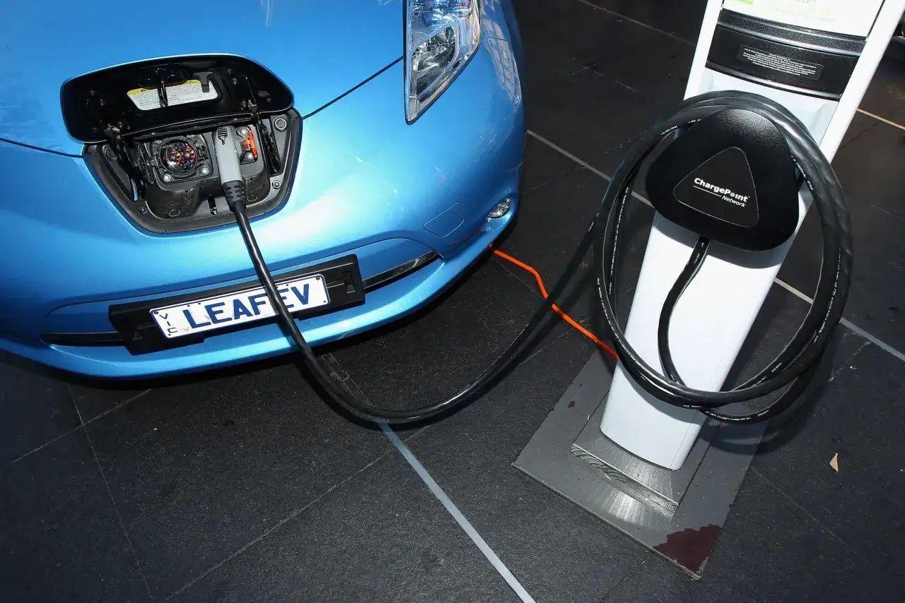 Niebieski Nissan Leaf podłączony do ładowarki. Ubezpieczenie tego ekologicznego auta jest kluczowe.