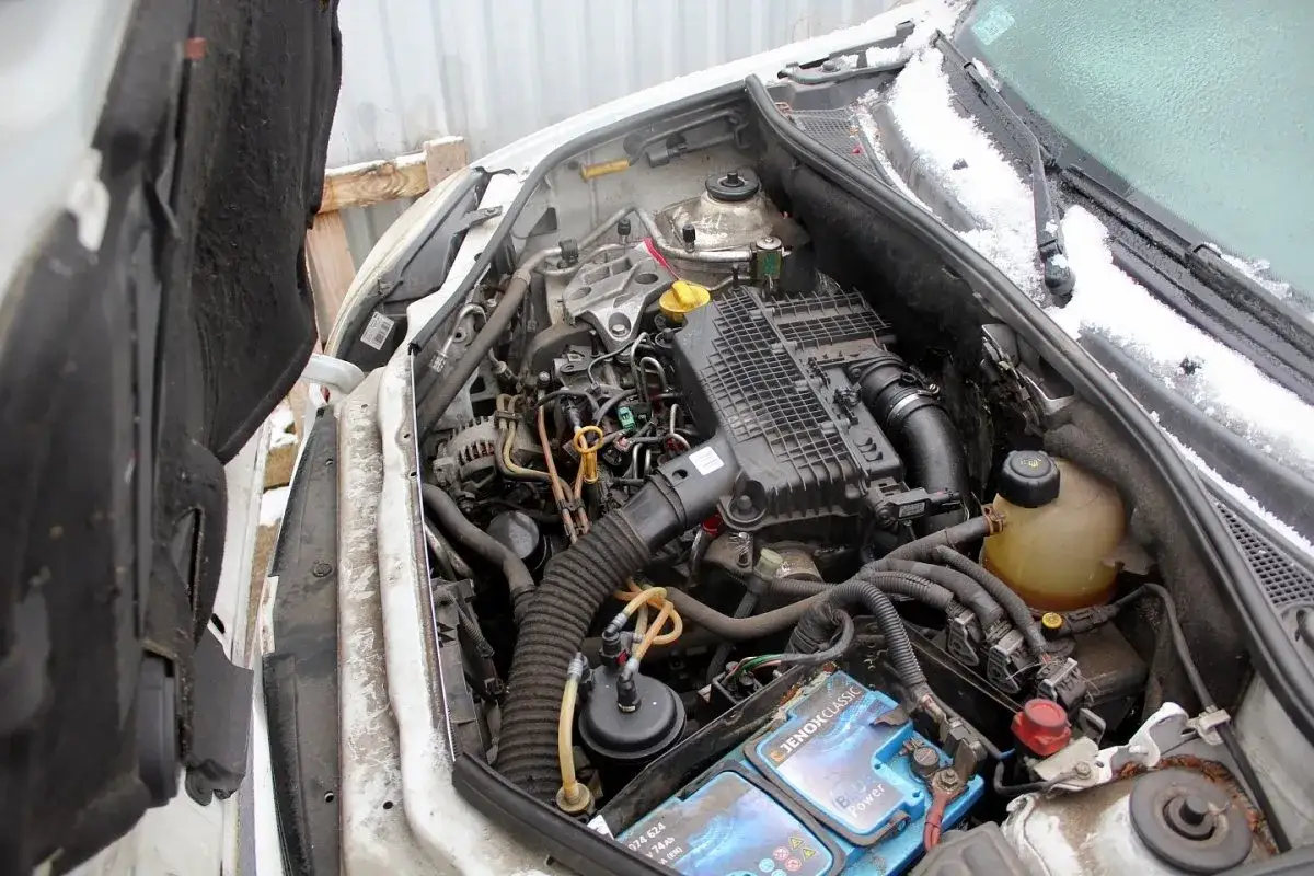 Silnik renault kangoo 1.5 dci z widocznym akumulatorem i przewodami. W tle śnieg.