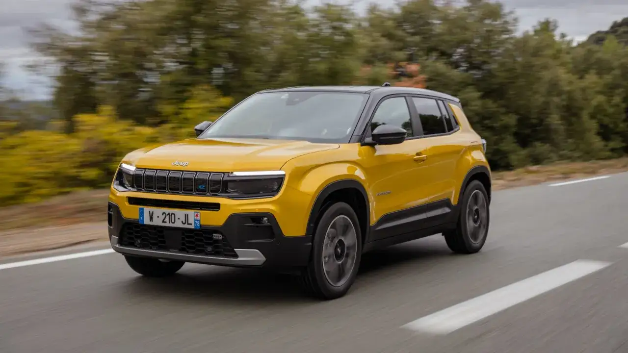 Żółty, mały SUV dla kobiety, Jeep Avenger, jedzie po drodze wśród drzew.