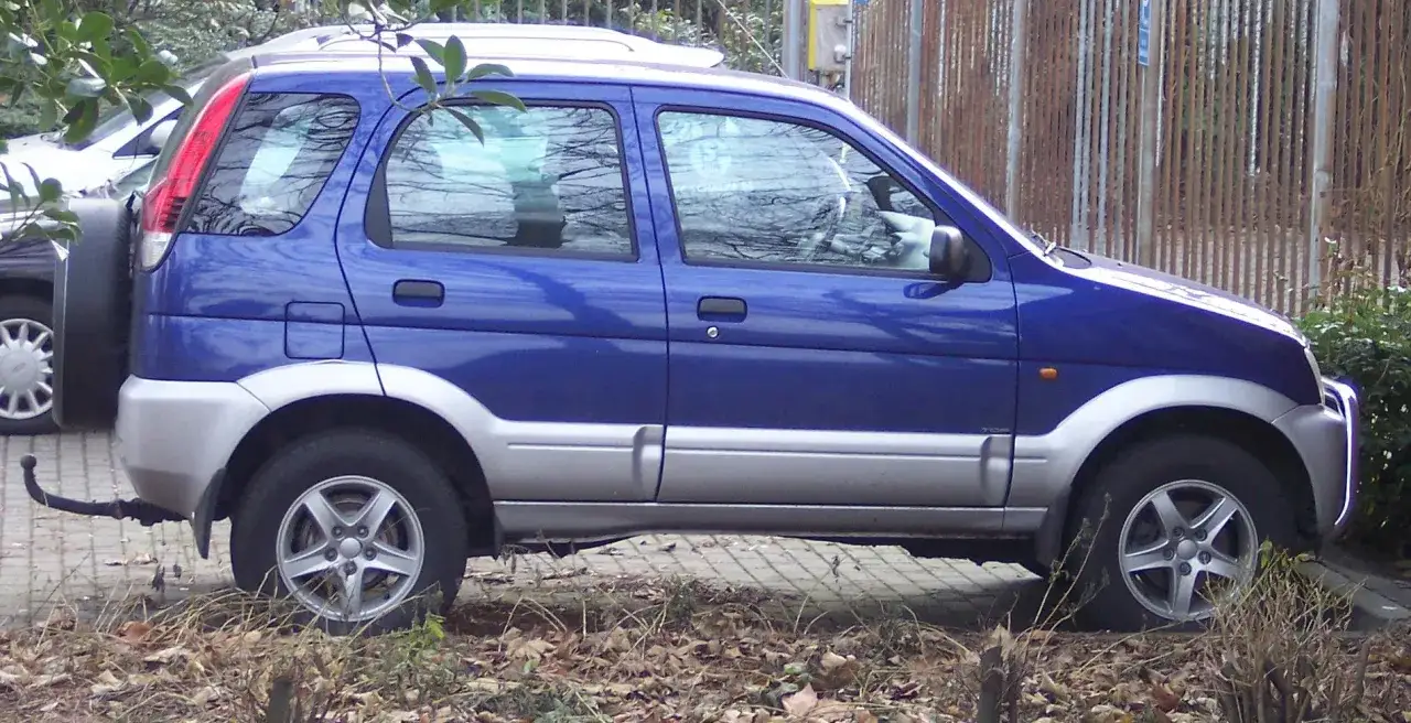 Niebieski Daihatsu Terios z zapasowym kołem z tyłu, zaparkowany na chodniku.