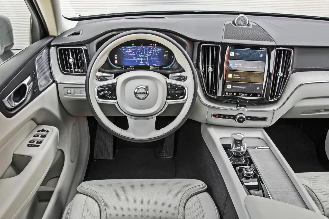 Wnętrze Volvo XC60 2026: nowoczesny kokpit z cyfrowymi zegarami, ekranem multimedialnym i jasną tapicerką.