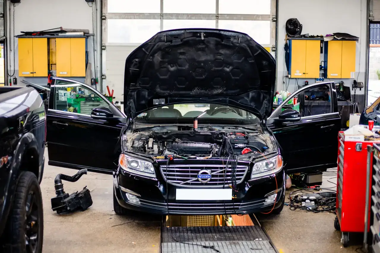 Warsztat samochodowy, czarne Volvo z otwartą maską i drzwiami, mechanik zastanawia się, jaka instalacja gazowa do samochodu będzie najlepsza.