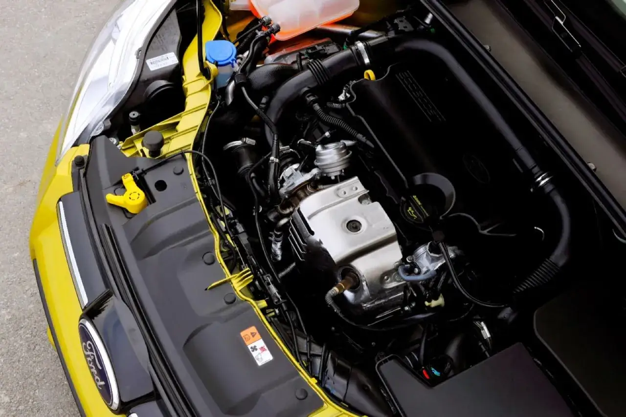 Silnik 1.0 Ecoboost w żółtym Fordzie. Widoczne elementy układu dolotowego, turbosprężarki i osłony silnika.