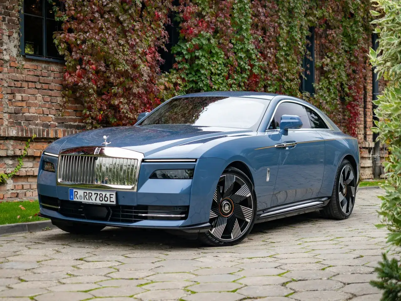 Niebieski Rolls-Royce z chromowaną atrapą chłodnicy i charakterystyczną figurką na masce. Zastanawiasz się nad rolls royce cena?