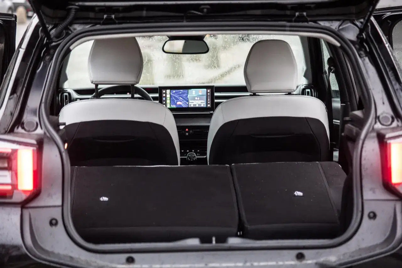Wnętrze Citroena C3 2025 z otwartym bagażnikiem, widoczne dwa jasne zagłówki i ekran multimedialny.