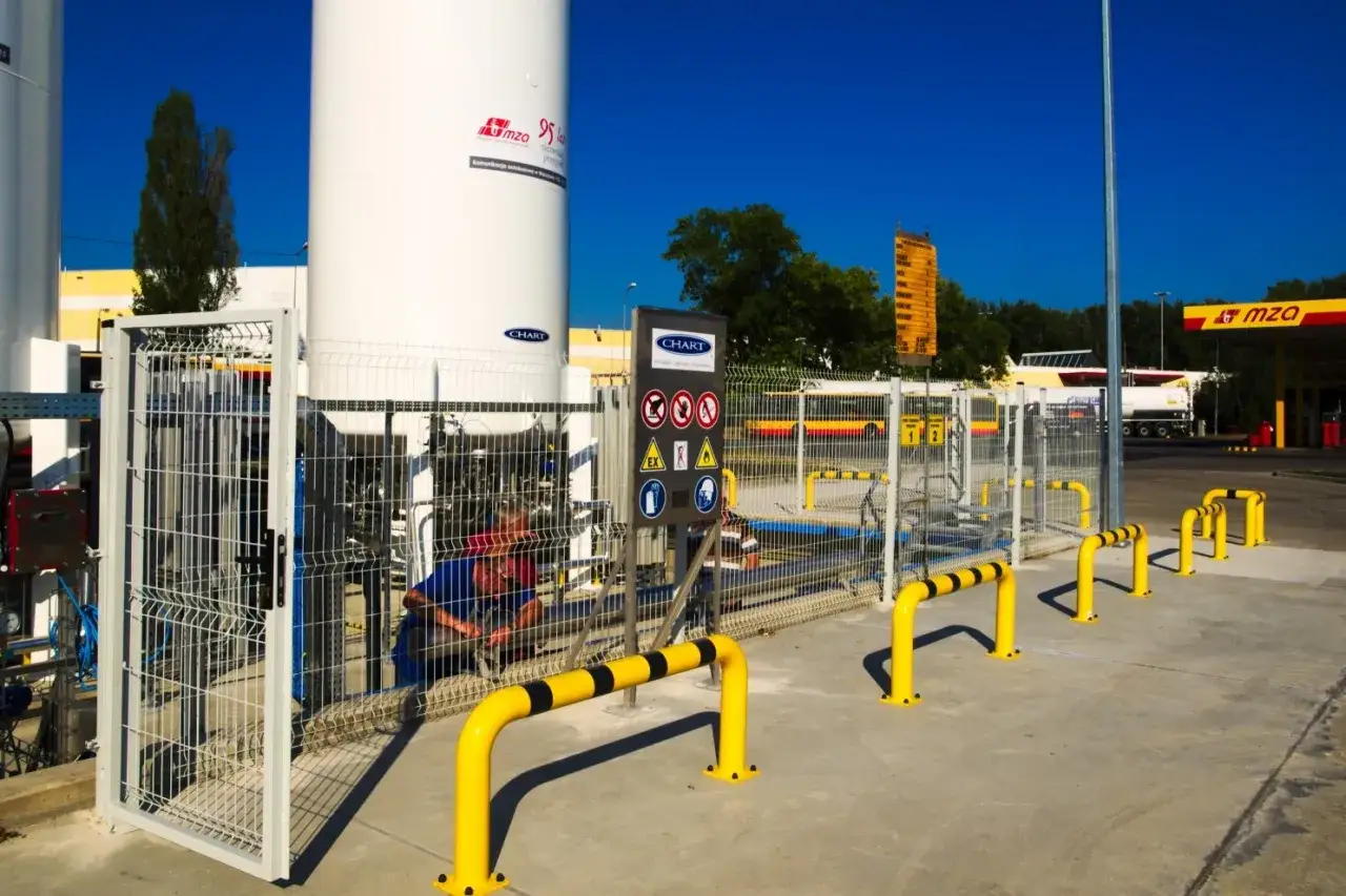Stacje CNG w Warszawie. Pracownik przy dużych zbiornikach z gazem ziemnym. W tle widoczna stacja paliw MZA.
