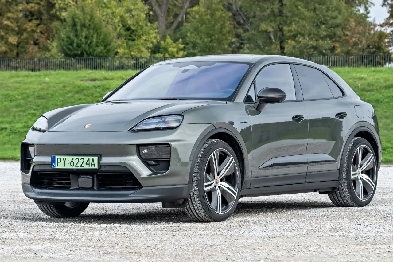 Szary Porsche Macan Electric na tle zieleni. Zastanawiasz się, ile kosztuje Porsche?