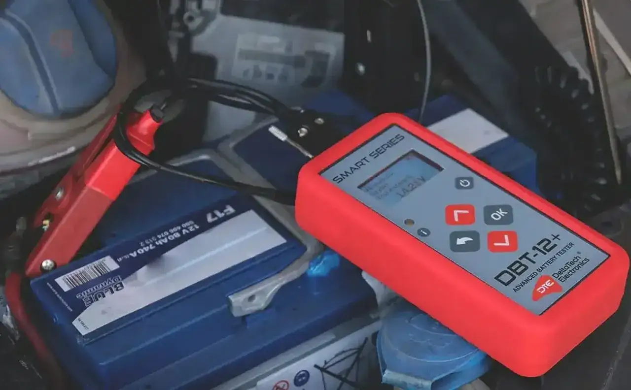 Tester akumulatora podłączony do baterii, wskazujący napięcie 14.25V. Pomoc w diagnostyce i odsiarczanie akumulatora.