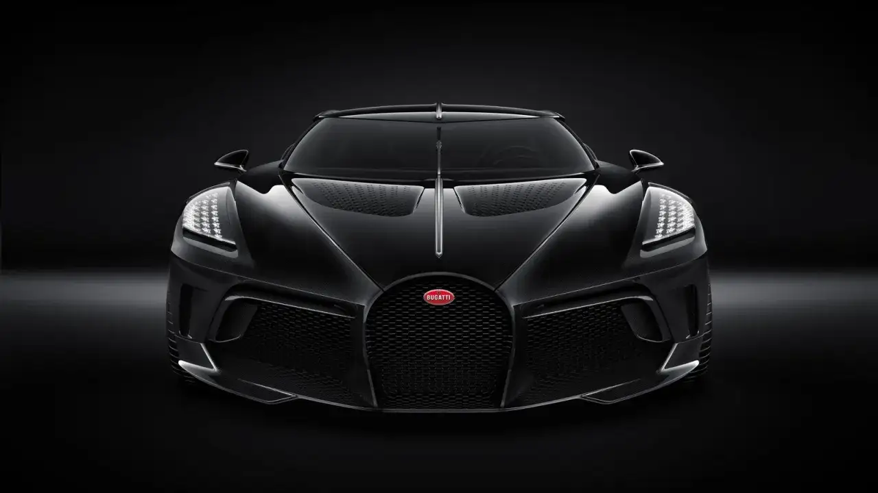 Przód czarnego Bugatti La Voiture Noire, z charakterystyczną kratą i światłami LED, prezentuje się majestatycznie na ciemnym tle.