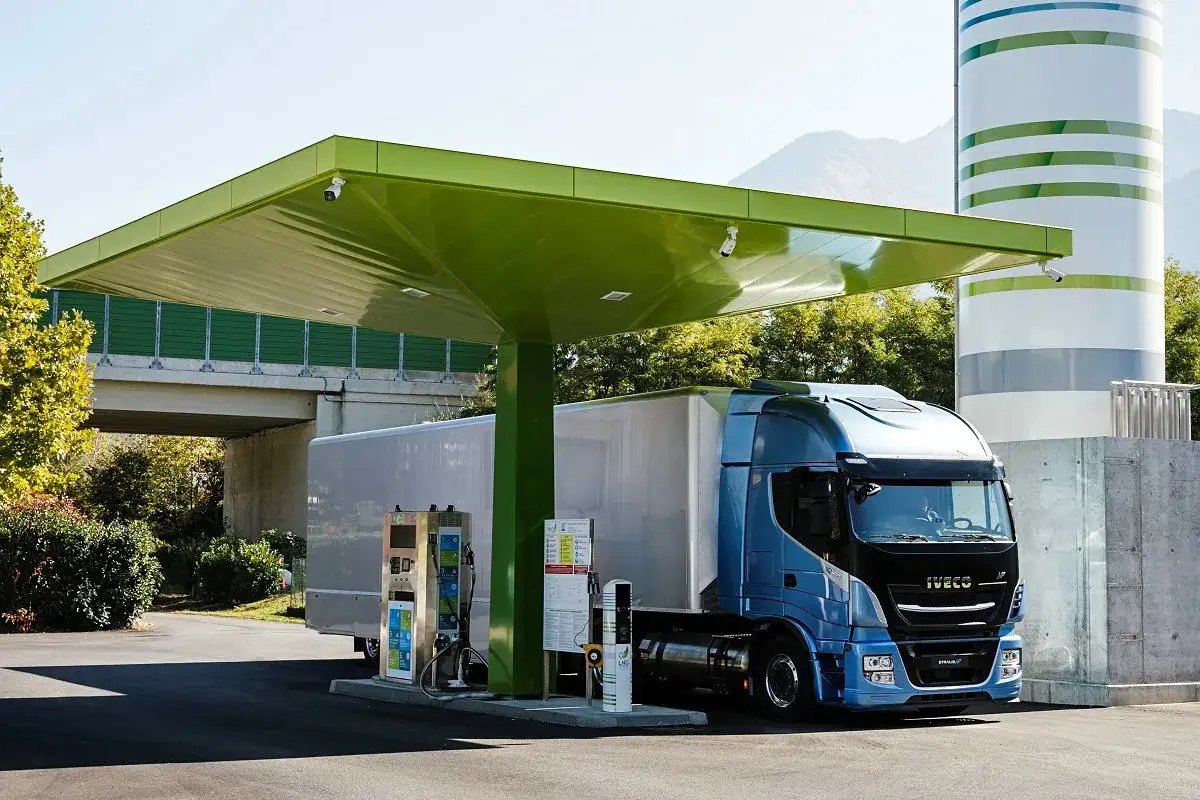 Ciężarówka Iveco zasilana gazem ziemnym (CNG) tankuje pod zieloną wiatą. Obok stacja LNG.