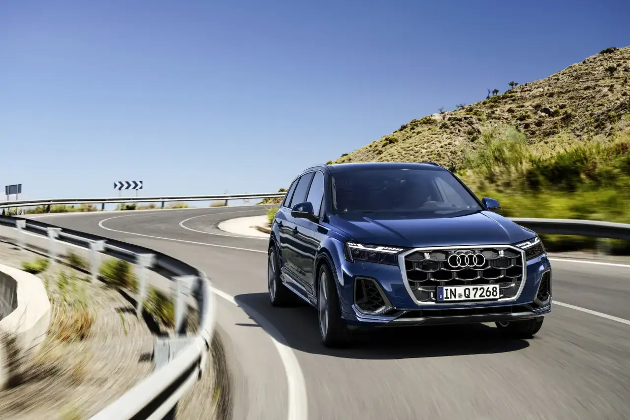 Granatowy Audi SQ7 sunie po krętej górskiej drodze.