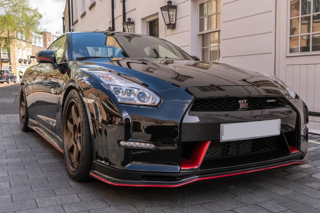 Czarny Nissan GTR Nismo z czerwonymi akcentami i brązowymi felgami. Zastanawiasz się nad nissan gtr cena?