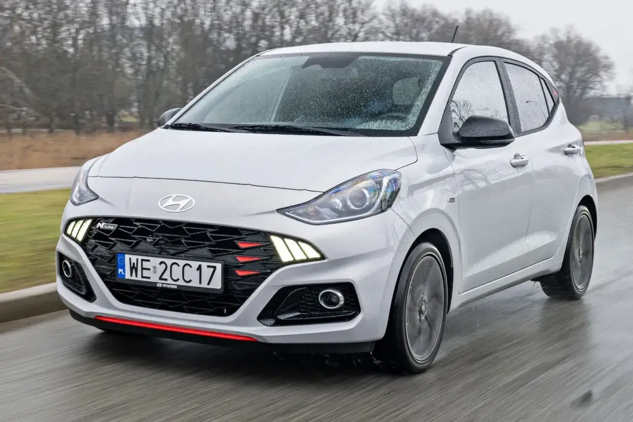 Biały Hyundai i10 N Line w ruchu, z widocznym grillem i światłami. Sprawdź aktualną hyundai i10 cena.