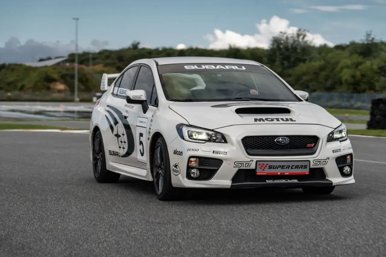 Białe Subaru STI z numerem 5 na torze wyścigowym, gotowe do akcji.