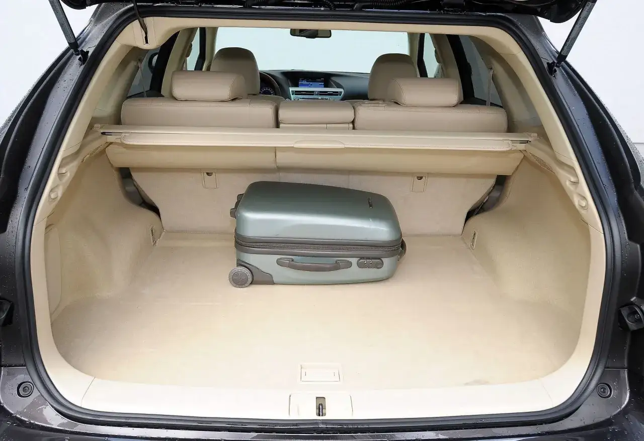 Bagażnik Lexus RX 350 gotowy na podróż. Jedna walizka czeka na załadunek.