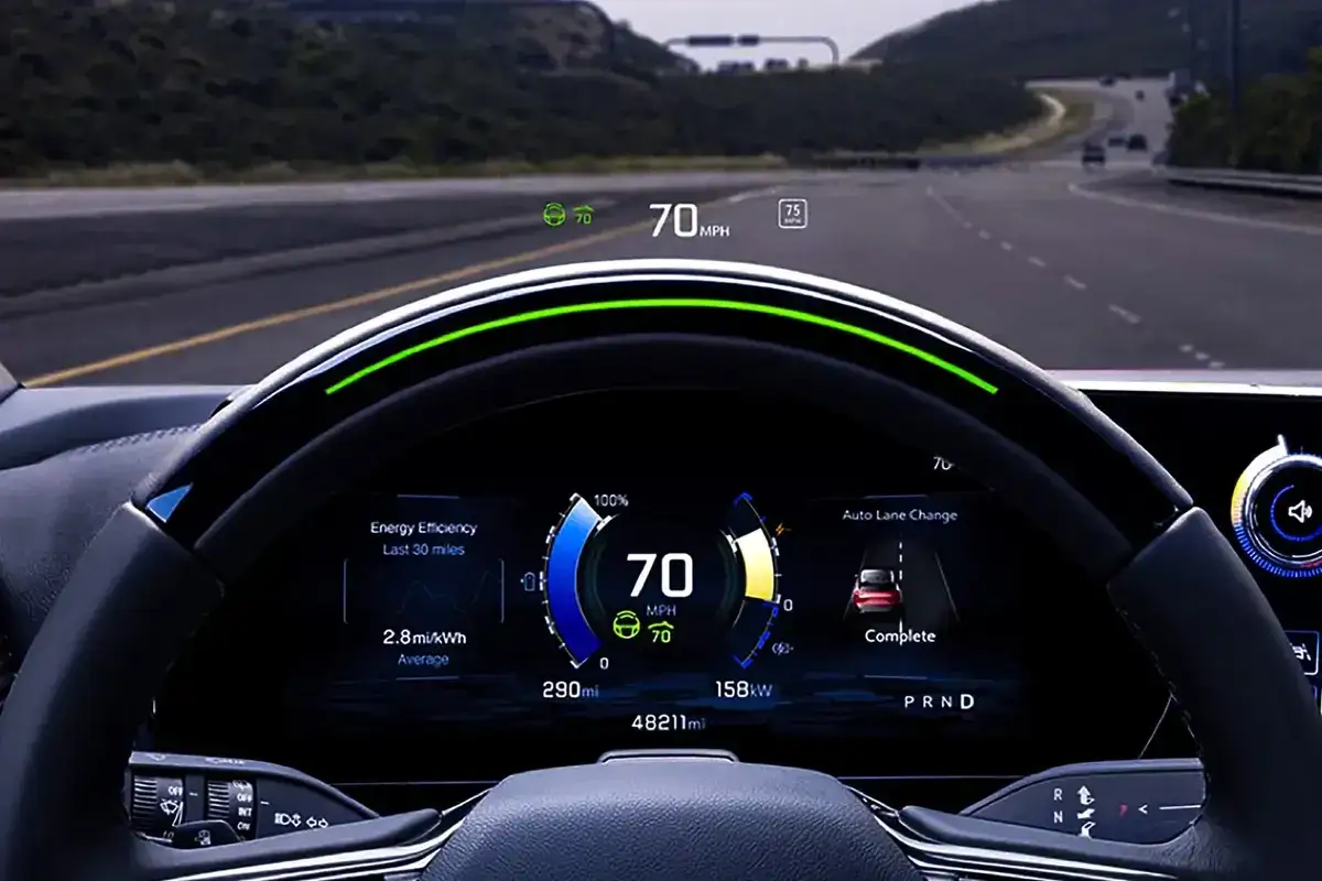 Widok z kabiny samochodu z wyświetlaczem HUD pokazującym prędkość 70 mph, efektywność energetyczną i asystenta zmiany pasa.