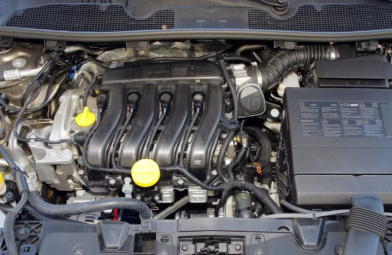 Silnik Renault Megane 3 z widocznym kolektorem dolotowym, cewkami zapłonowymi i żółtymi korkami.