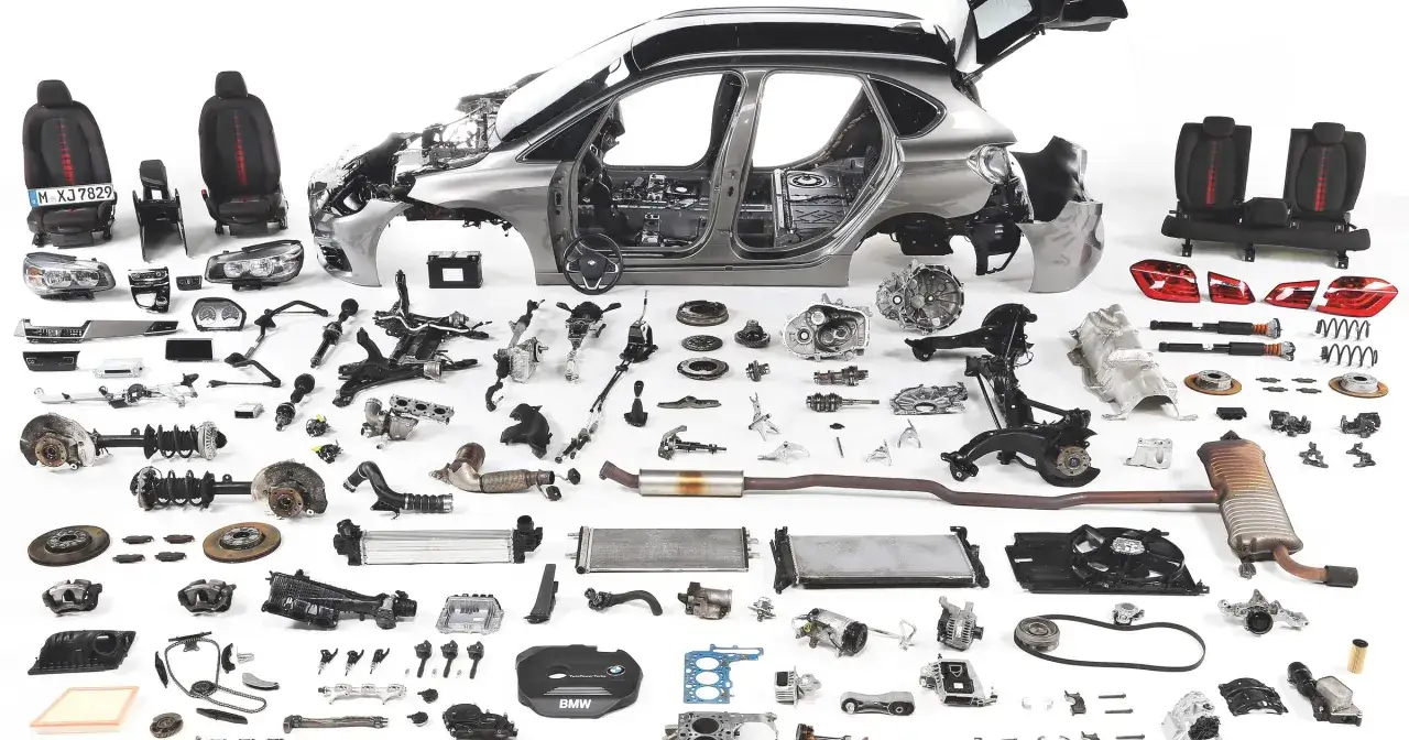 Rozłożone części BMW 218i: karoseria, fotele, silnik, skrzynia biegów, zawieszenie, hamulce, chłodnice i inne podzespoły.