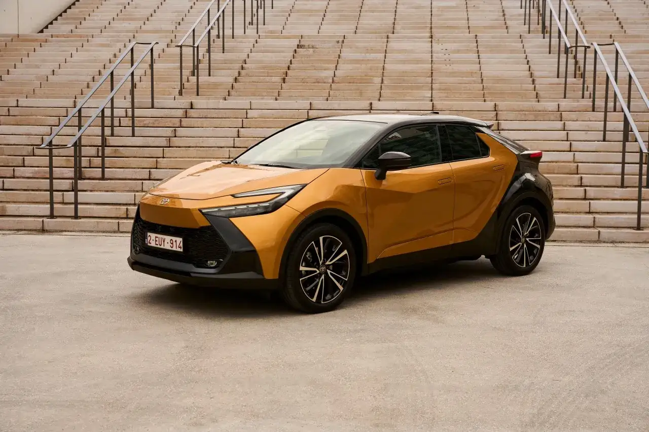 Złoty Toyota C-HR na tle schodów. Sprawdź atrakcyjną toyota chr cena i wybierz swój wymarzony model.