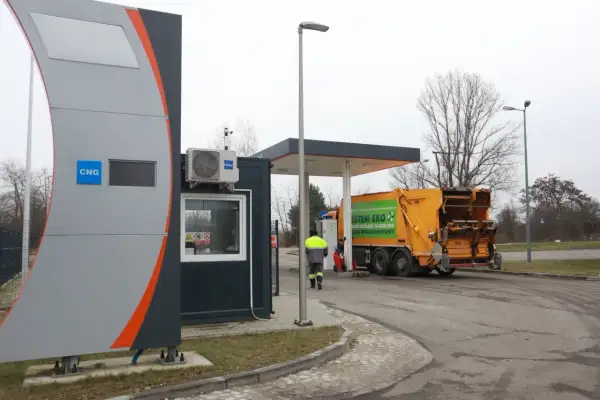 Stacja paliw z oznaczeniem CNG, gdzie można tankować gaz. Obok żółta śmieciarka z napisem "System Eko".