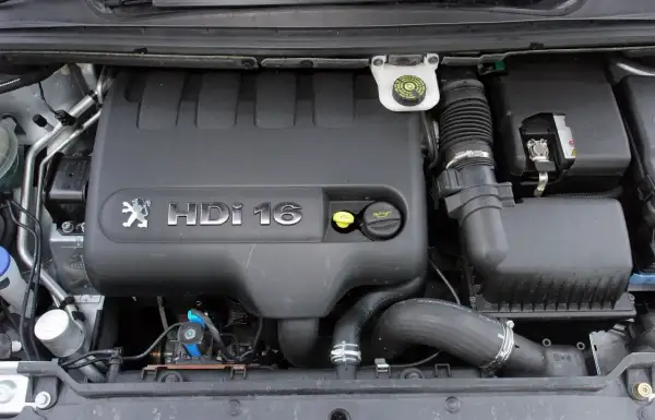 Silnik Peugeot 307 2.0 HDI 16V. Widoczny czarny plastikowy kolektor, przewody i akumulator.