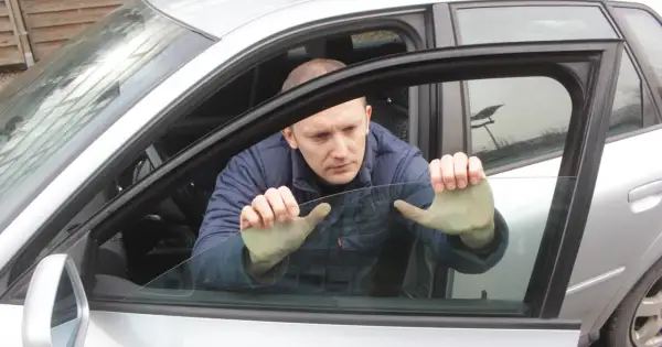 Mężczyzna próbuje podnieść szybę elektryczną w samochodzie, która nie chce się podnieść.