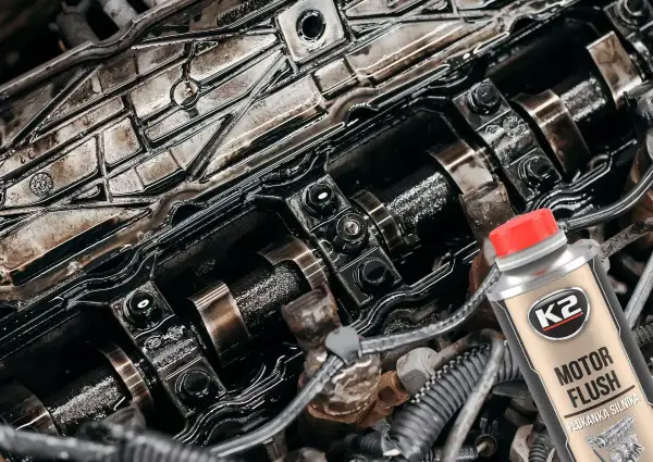 Zabrudzony silnik samochodowy i butelka K2 Motor Flush – dobra płukanka do silnika, która przywróci mu czystość i sprawność.