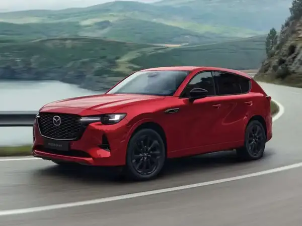 Czerwona Mazda CX-60 3.3 diesel pokonuje zakręt na malowniczej drodze.